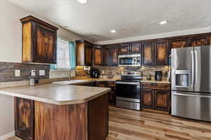 Updated kitchen with stained cabinetry, stainless steel appliances, and an organized reach-in pantry.