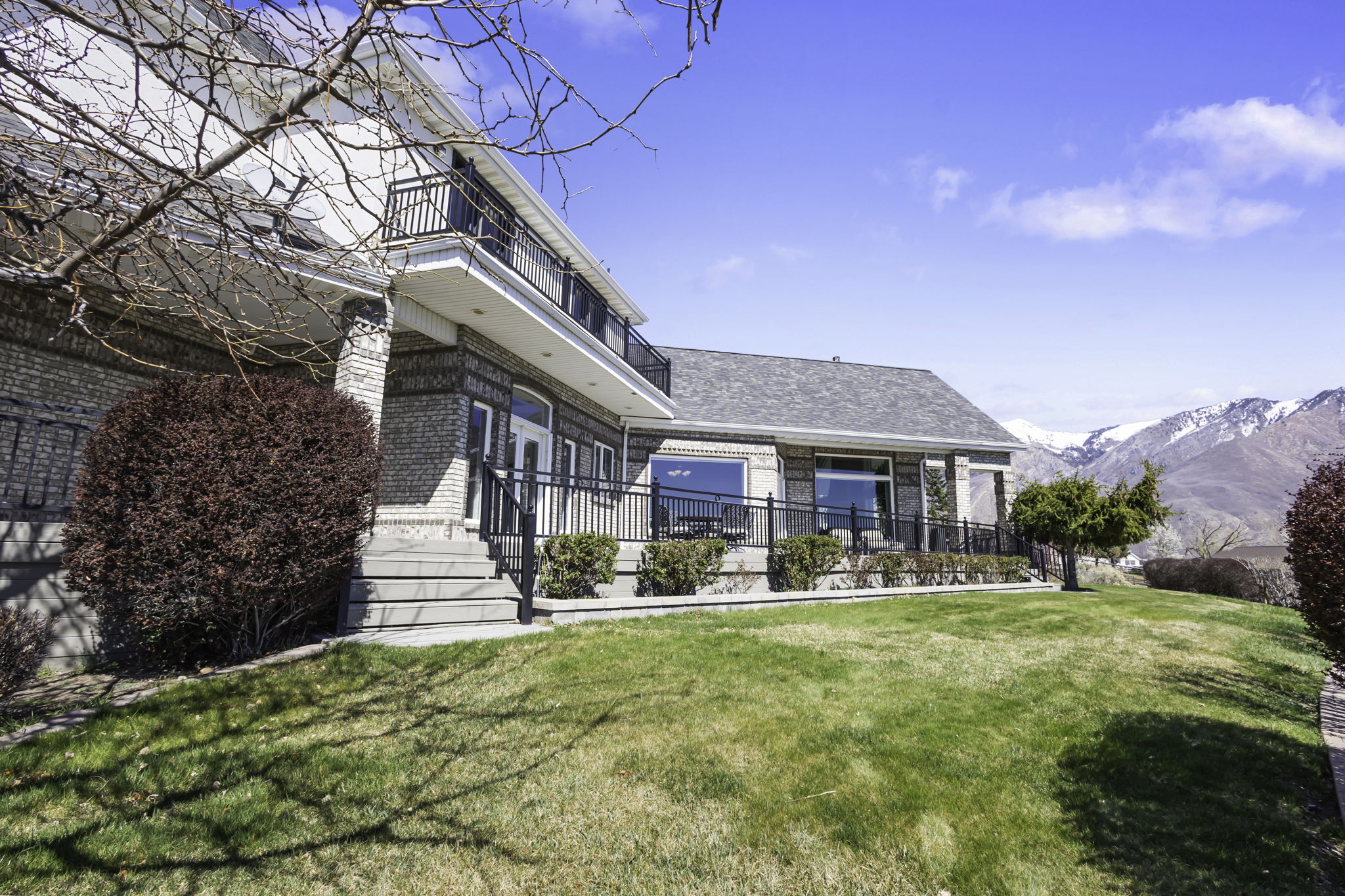 Rear view of house with brick siding, a lawn, and a mountain view