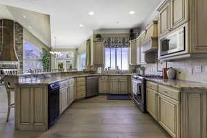 Kitchen featuring a breakfast bar area, stainless steel appliances, light stone countertops, a peninsula, and backsplash