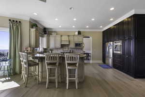 Kitchen featuring a peninsula, arched walkways, a breakfast bar area, light stone countertops, and stainless steel appliances