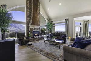 Living area featuring vaulted ceiling, light wood finished floors, recessed lighting, a fireplace, and a ceiling fan