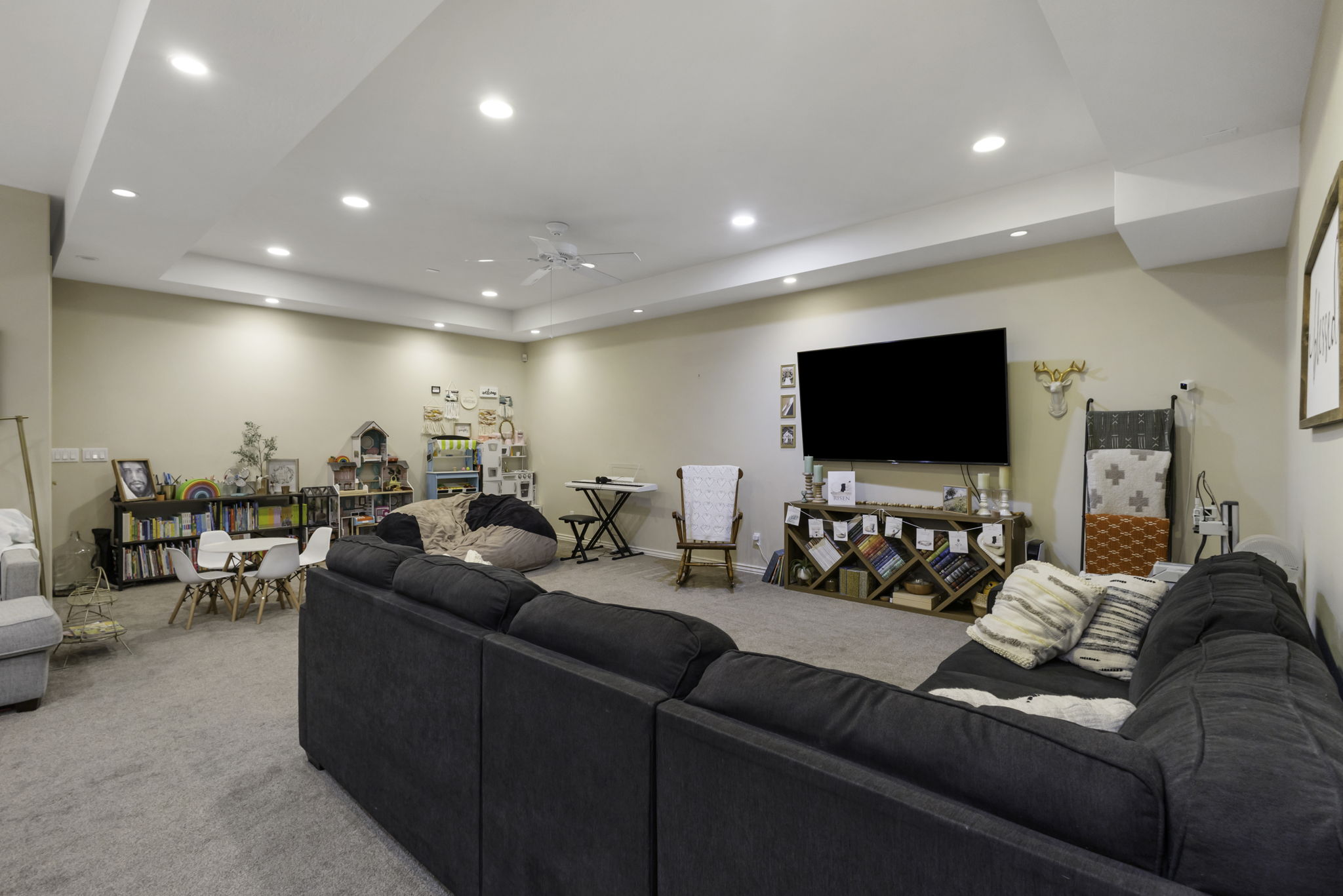 Living room with light carpet, a ceiling fan, recessed lighting, and a raised ceiling