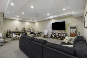 Living room with light carpet, a ceiling fan, recessed lighting, and a raised ceiling