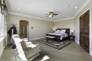 Bedroom with ornamental molding, arched walkways, light wood-style flooring, a ceiling fan, and recessed lighting