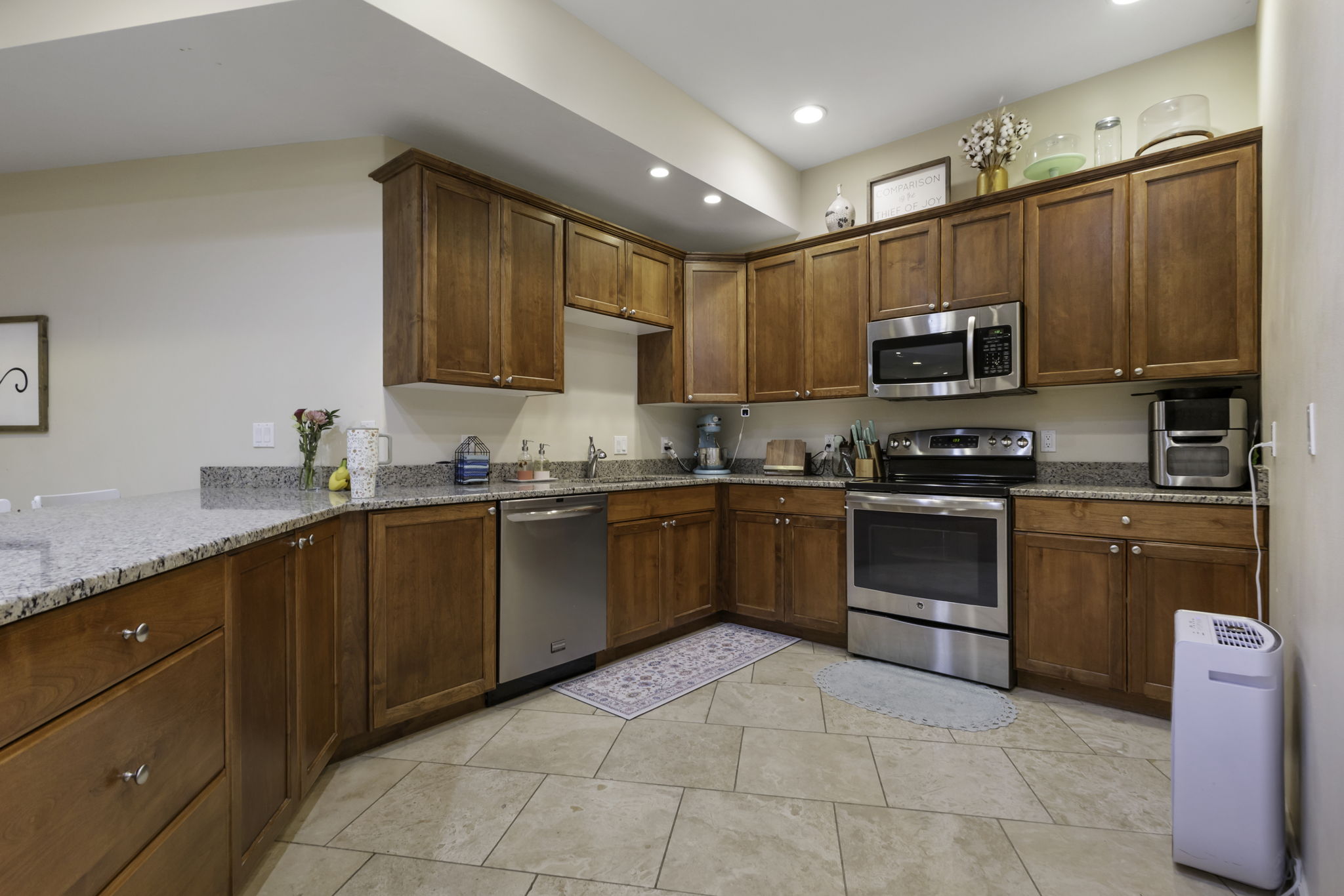 Kitchen featuring stainless steel appliances, wood finish cabinets, light stone counters, and recessed lighting