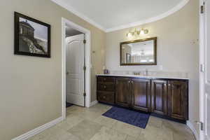 Bathroom with vanity, ornamental molding, and light tile patterned flooring
