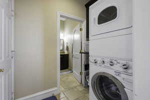 Laundry room with stone tile flooring and stacked washer and dryer
