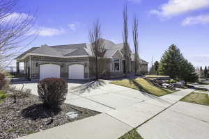 View of front of house with concrete driveway, a garage, a shingled roof, brick siding, and a gate