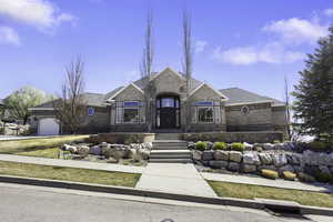 French country inspired facade featuring an attached garage, a shingled roof, brick siding, and driveway