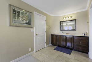Bathroom with vanity, crown molding, and light tile patterned floors