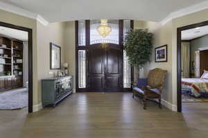 Entryway featuring crown molding, light wood-style floors, and hanging lights