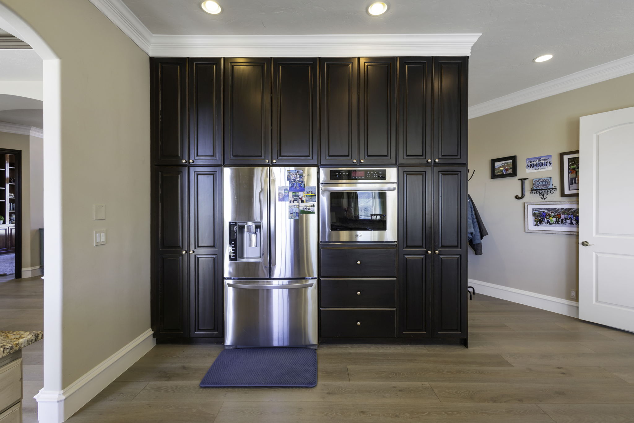 Kitchen featuring crown molding, stainless steel appliances, dark wood finish cabinets, light wood-style floors, and arched walkways