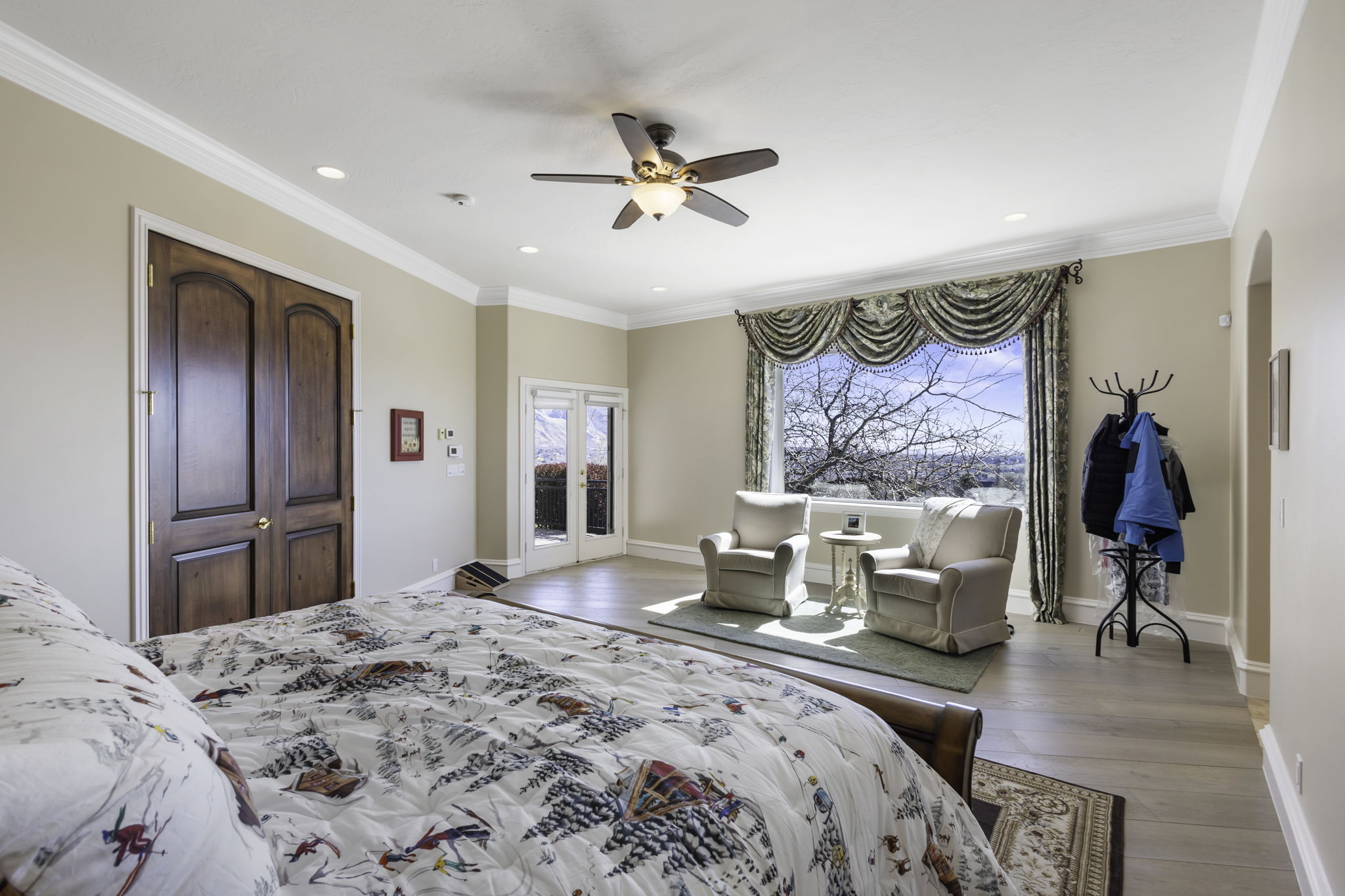 Bedroom featuring access to exterior, light wood-type flooring, ornamental molding, ceiling fan, and arched walkways