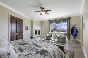 Bedroom featuring access to exterior, light wood-type flooring, ornamental molding, ceiling fan, and arched walkways