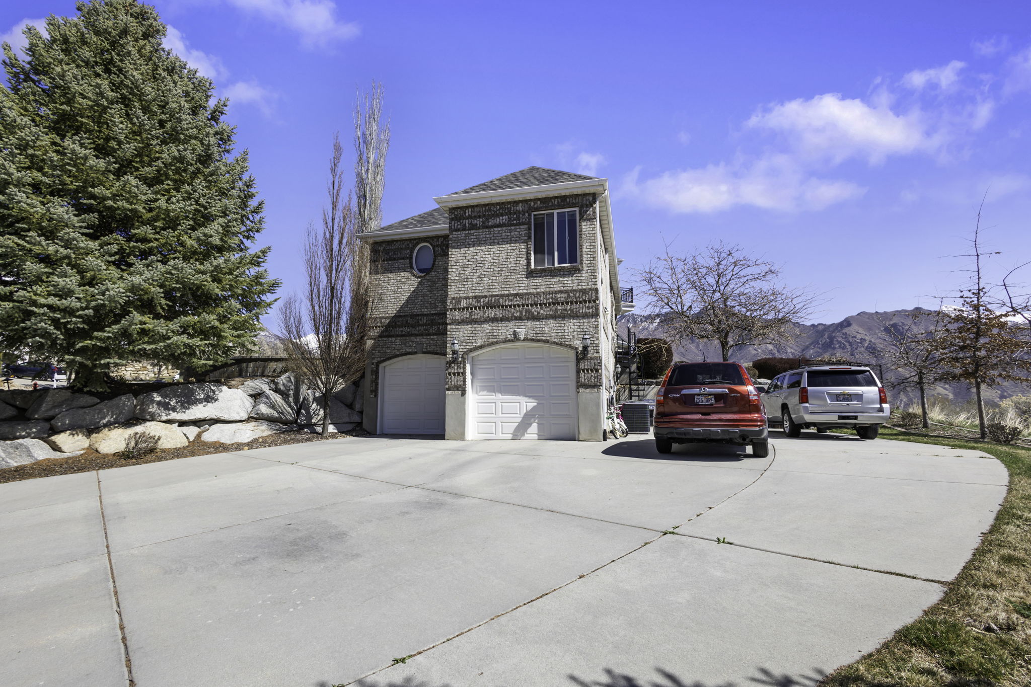 View of side of property with concrete driveway, brick siding, an attached garage, and a mountain view