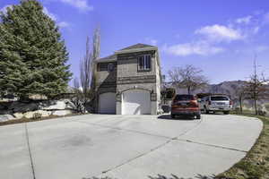 View of side of property with concrete driveway, brick siding, an attached garage, and a mountain view