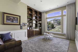 Living area with built in shelves, wainscoting, a decorative wall, and light wood finished floors