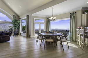 Dining area featuring healthy amount of natural light, light wood-style floors, suspended lighting, crown molding, and a mountain view