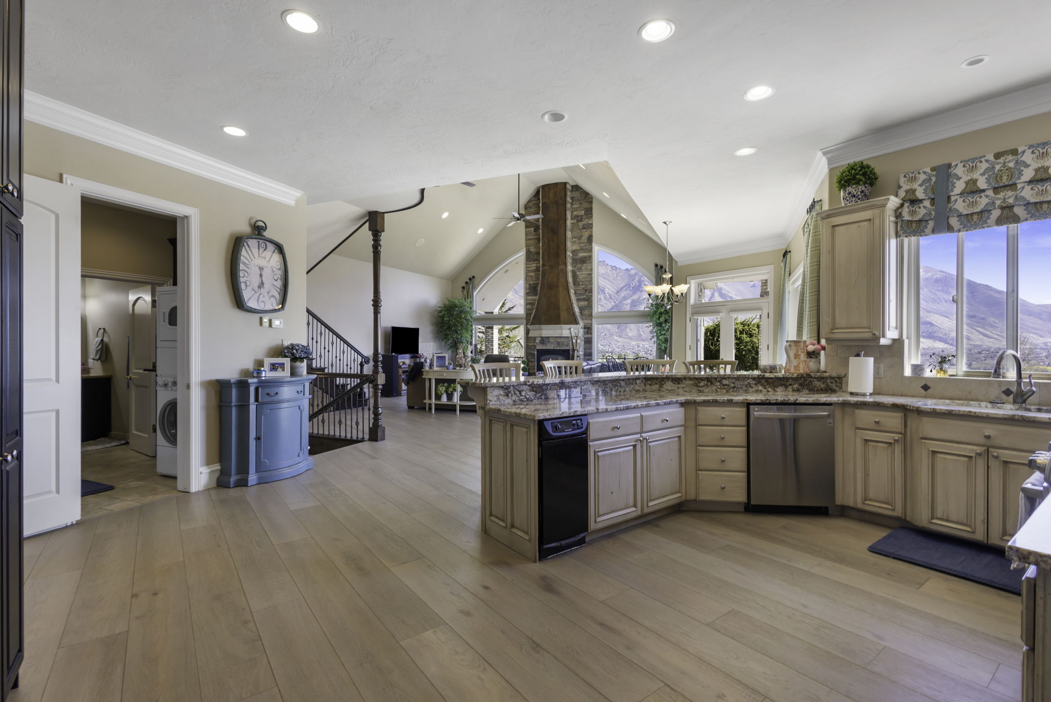 Kitchen featuring a peninsula, ceiling fan, vaulted ceiling, ornamental molding, and light stone countertops