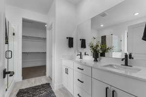 Full bathroom featuring a stall shower, double vanity, a spacious closet, recessed lighting, and light wood-type flooring