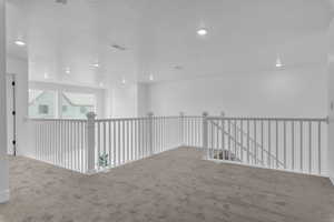 Hall with a textured ceiling, carpet, an upstairs landing, and recessed lighting