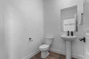 Half bathroom with toilet and wood finished floors