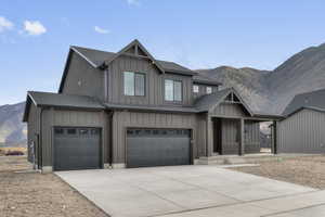 View of front of property featuring board and batten siding, a mountain view, concrete driveway, a garage, and covered porch