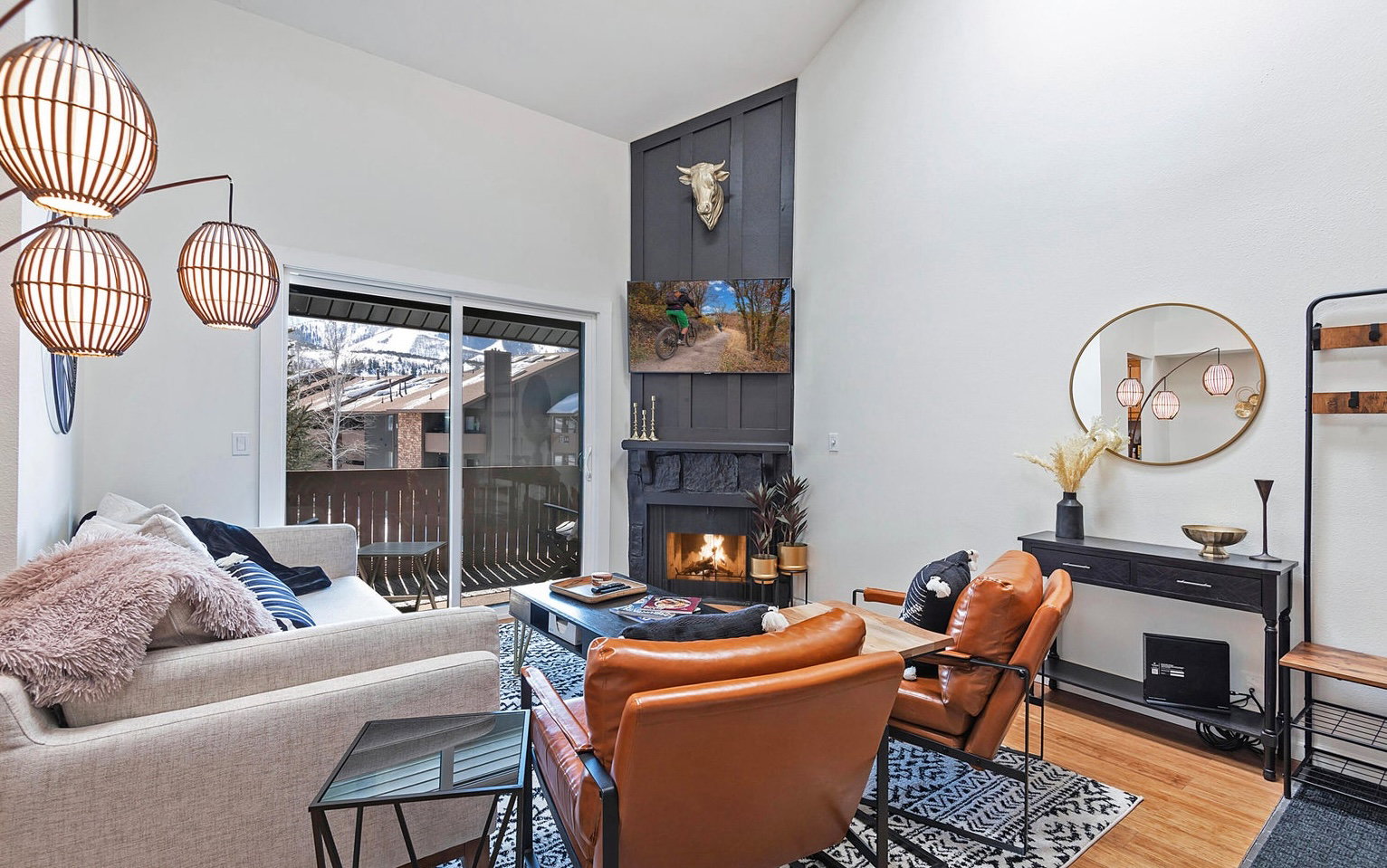 Living area with vaulted ceiling, light wood-type flooring, and a warm lit fireplace