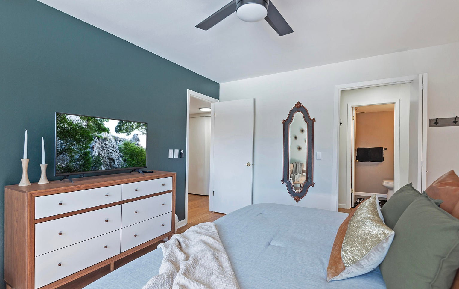 Bedroom with ensuite bathroom, light wood-type flooring, and ceiling fan