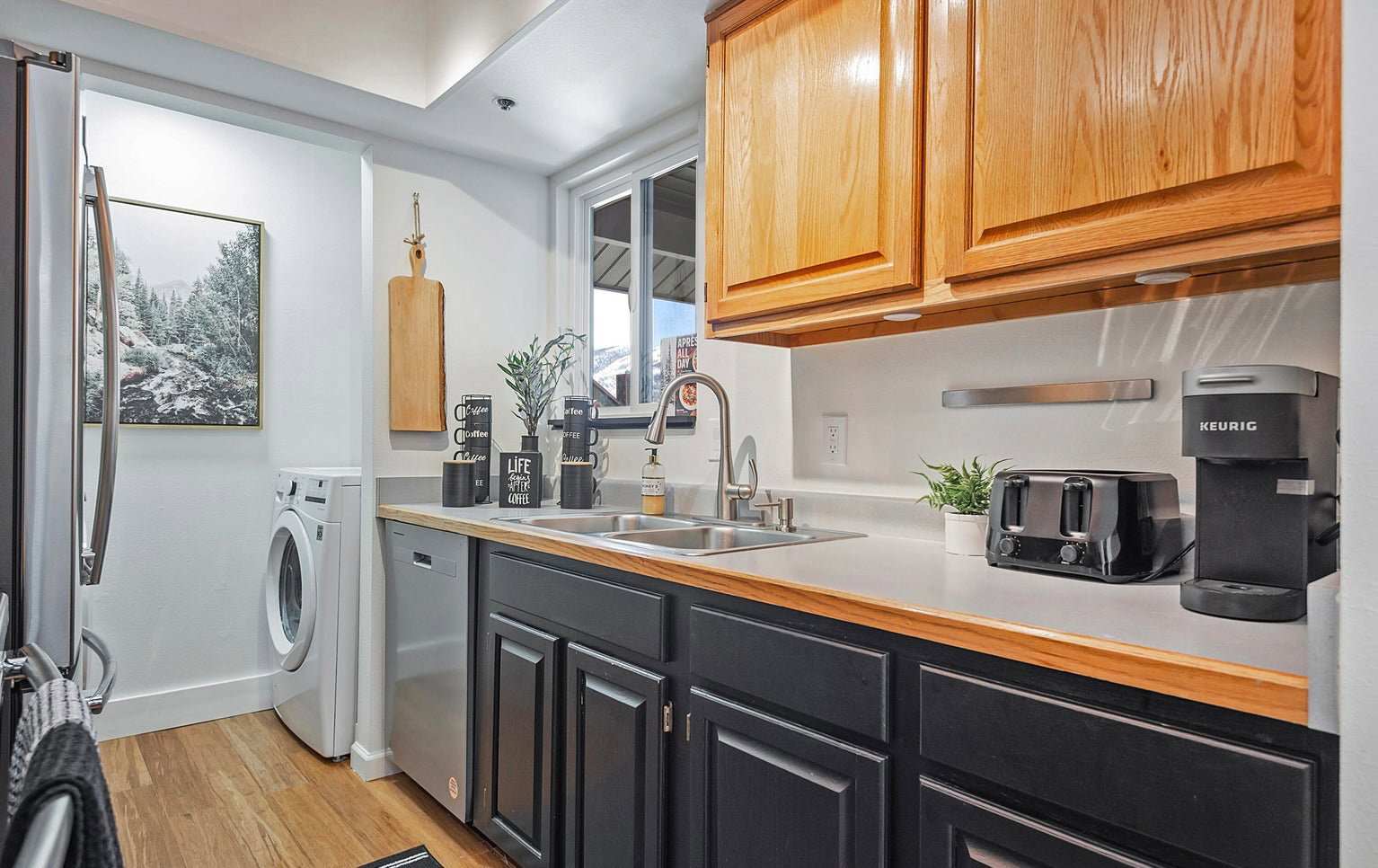 Kitchen featuring light countertops, washer / dryer, stainless steel appliances, and light wood-style flooring