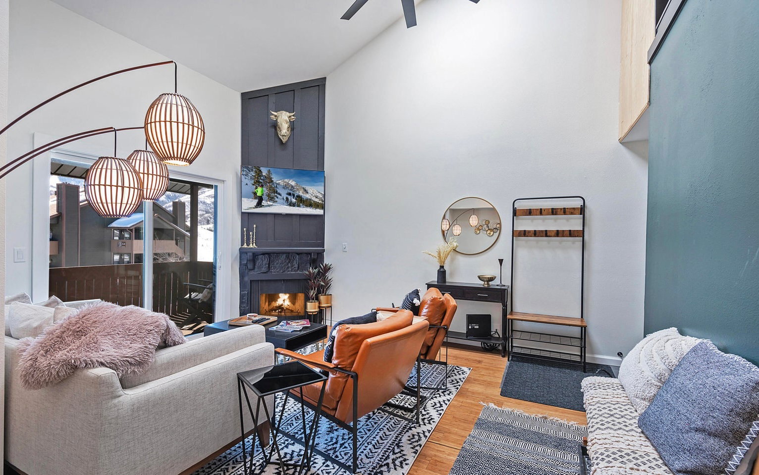 Living area with a high ceiling, light wood-style floors, a high end fireplace, and a ceiling fan