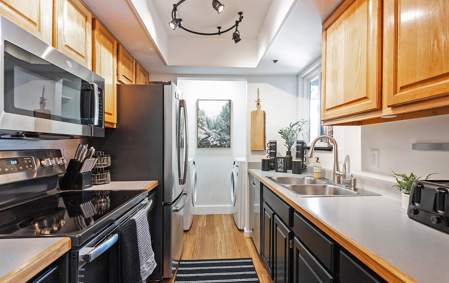 Kitchen featuring stainless steel appliances, light countertops, light wood-style flooring, and dark cabinetry