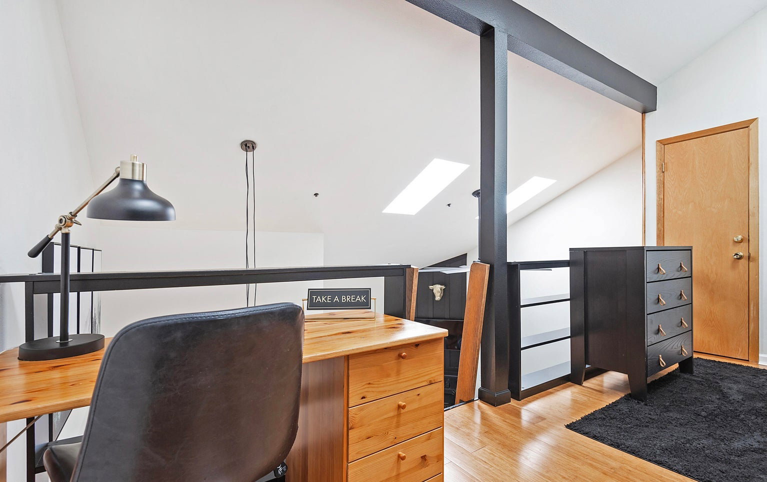 Office space featuring a skylight, vaulted ceiling, and light wood-style flooring