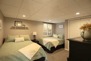 Carpeted bedroom with a closet, a drop ceiling, and recessed lighting