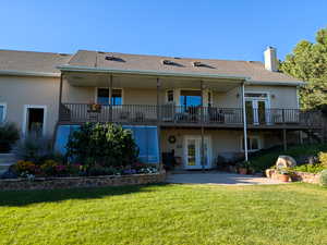 Rear view of house with french doors, stucco siding, a yard, and a chimney