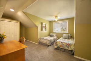 Carpeted bedroom with a closet, lofted ceiling, and ceiling fan