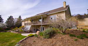 Rear view of property with stucco siding, a chimney, a yard, a patio area, and a balcony