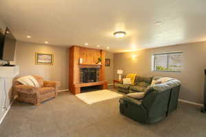 Carpeted living room featuring a fireplace with raised hearth, recessed lighting, and a textured ceiling