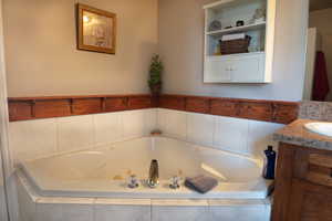 Primary full bath with vanity and a jetted tub