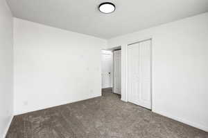 Unfurnished bedroom with dark carpet and a closet