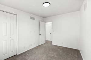 Unfurnished bedroom featuring dark colored carpet and a closet