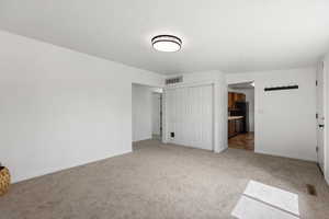 Unfurnished bedroom featuring a closet, light colored carpet, and ensuite bathroom