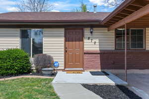 View of exterior entry featuring a shingled roof