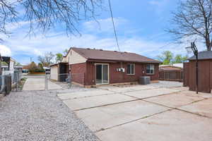 Rear view of property featuring a gate, an outdoor structure, brick siding, and roof with shingles