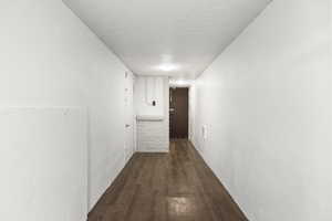 Hallway featuring a textured ceiling and dark wood finished floors