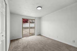 Carpeted spare room featuring baseboards and a textured ceiling