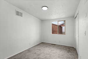 Carpeted spare room with baseboards and a textured wall