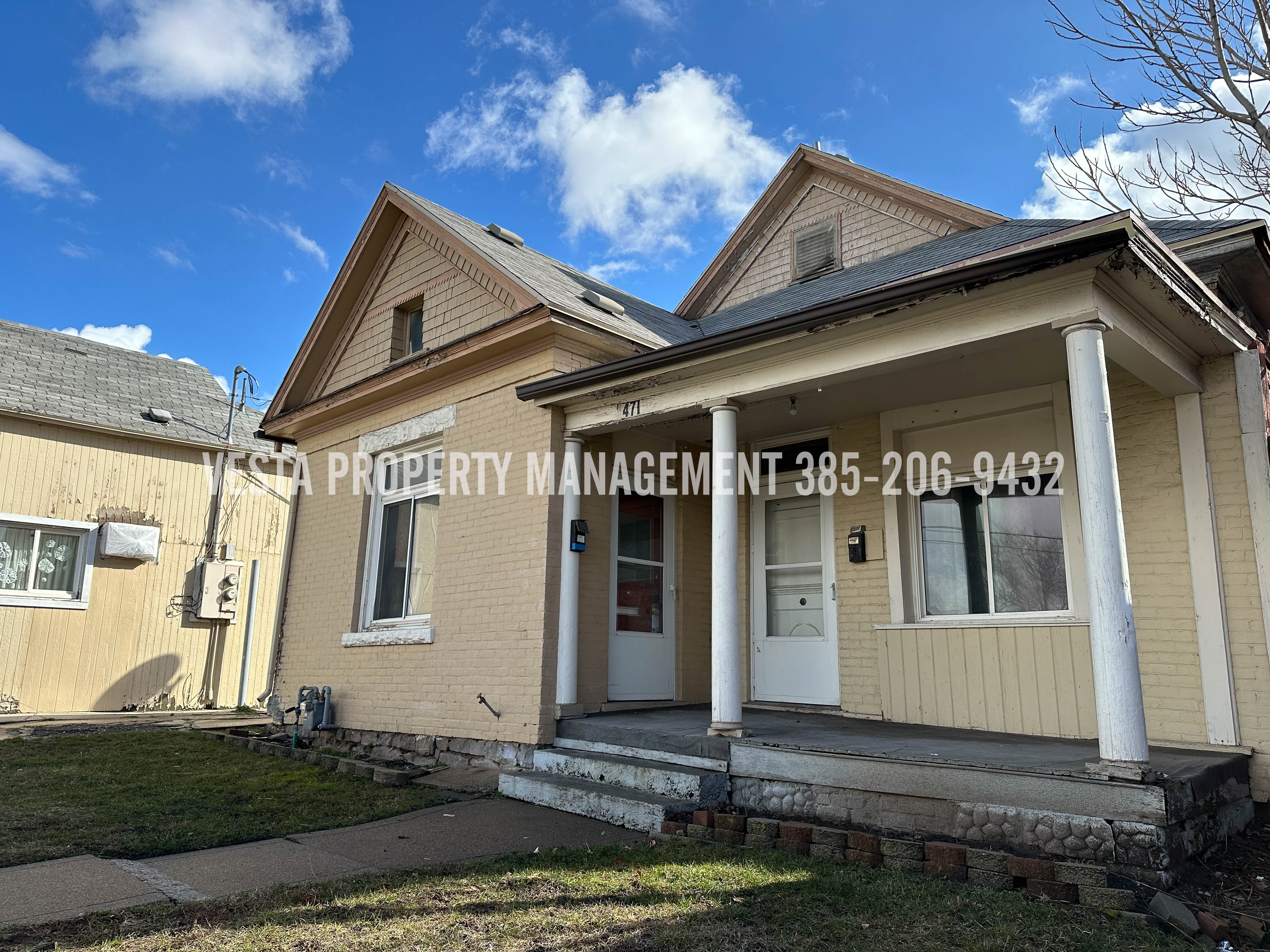 View of front facade with brick siding, covered porch, and a front yard