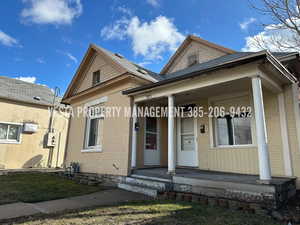 View of front facade with brick siding, covered porch, and a front yard