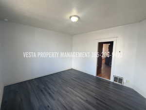Empty room with dark wood finished floors and a textured ceiling